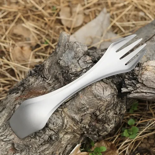 Titan-Spork auf einem Baumstamm, Gabelseite mit Schneidkante im Vordergrund