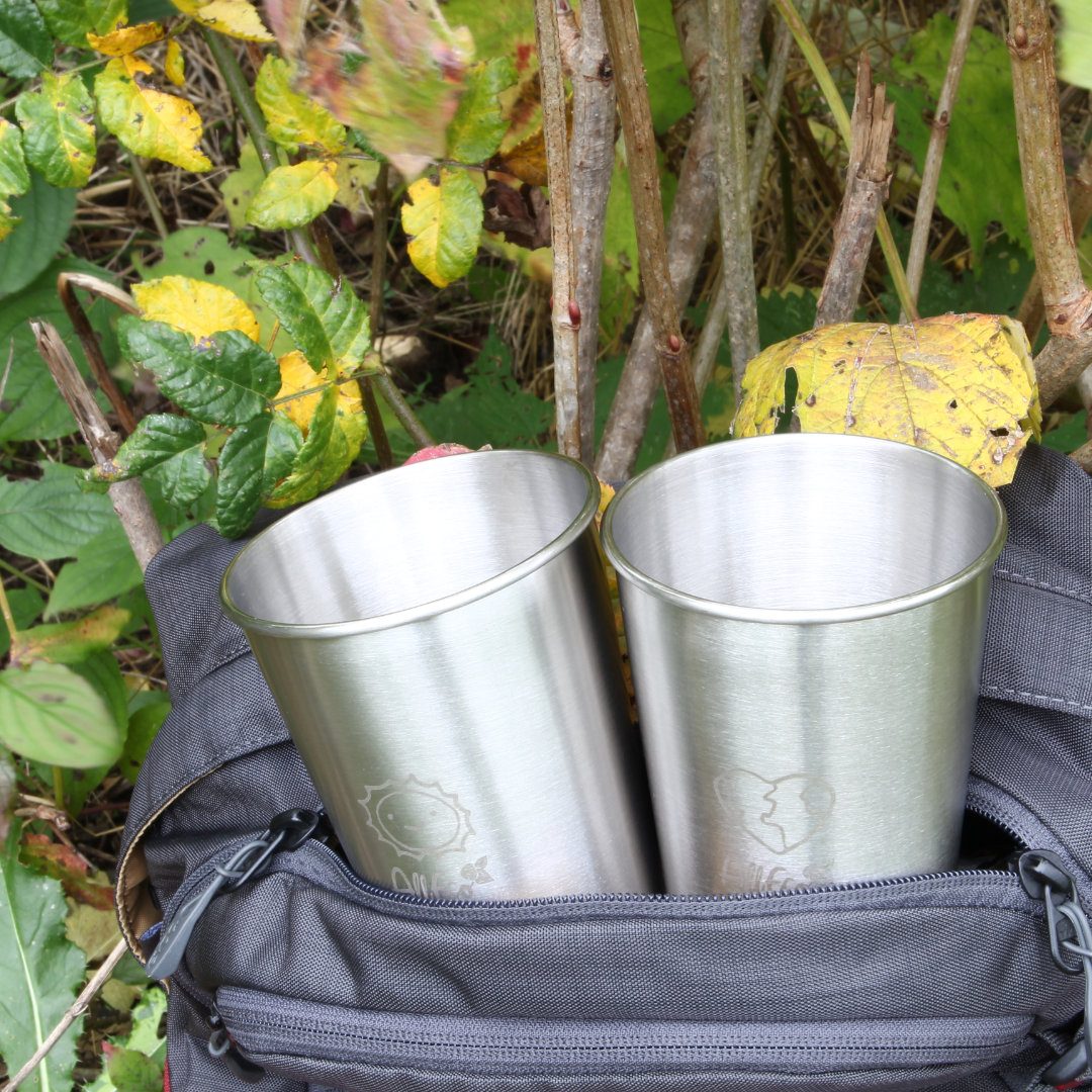 Zwei Edelstahlbecher mit geprägten Symbolen in der Vordertasche eines Rucksacks