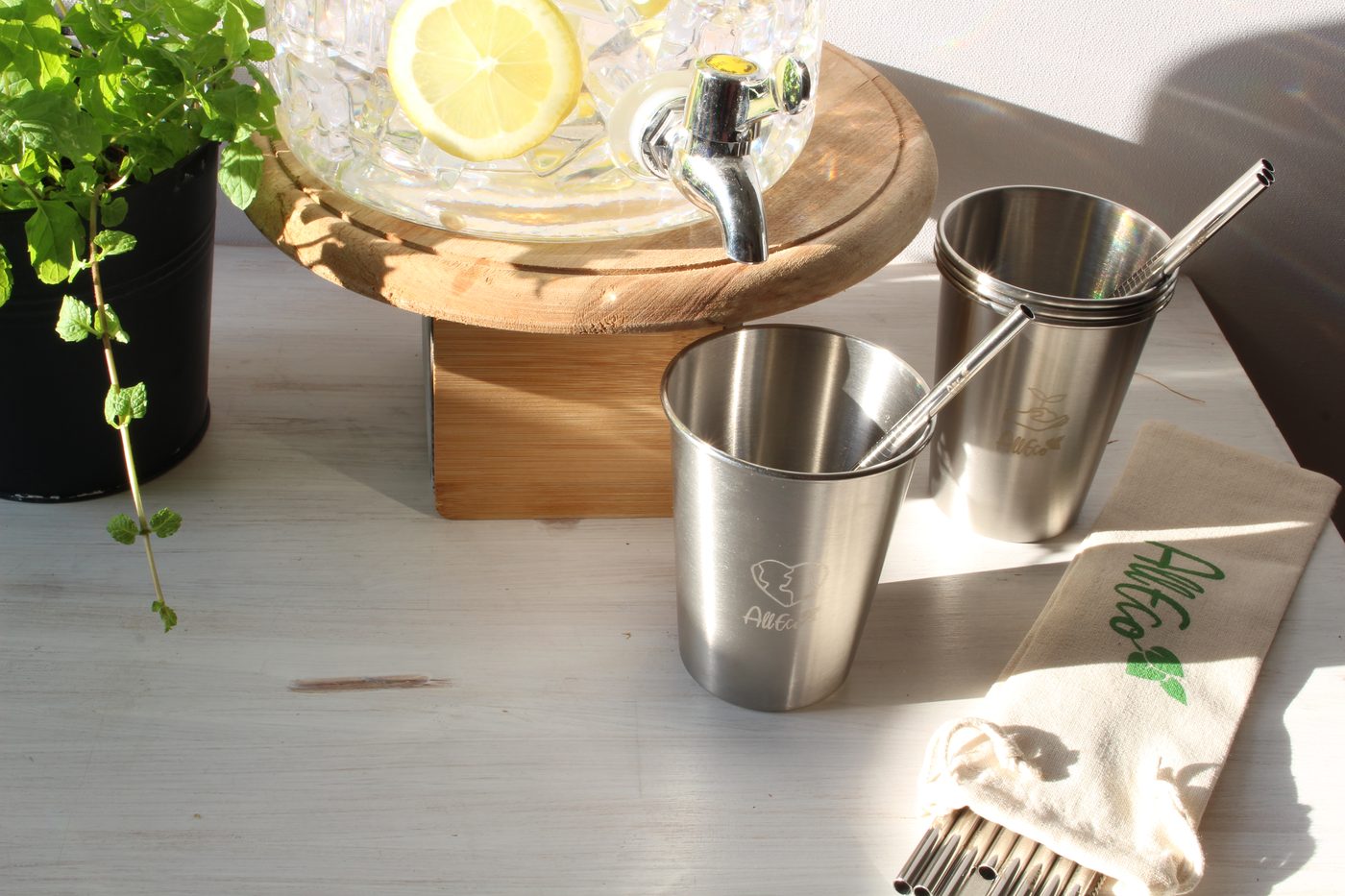 Edelstahl-Trinkbecher mit Edelstahl-Strohhalmen vor einem Getränkespender mit Zitronenwasser