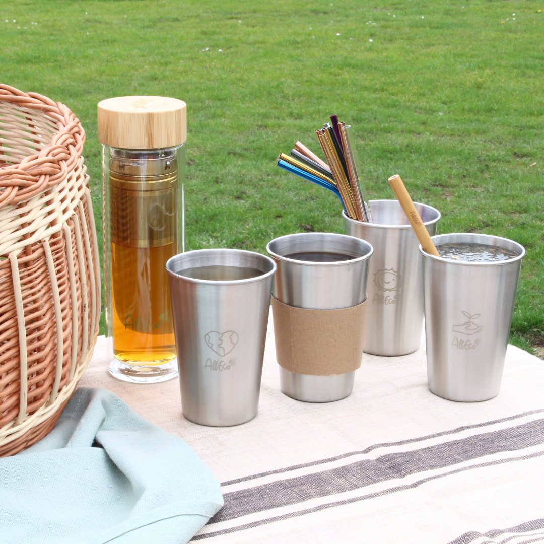 Picknick im Park mit Edelstahlbechern, Teebereiter, Strohhalmen und Picknickkorb