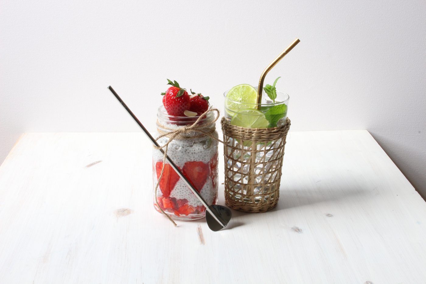 Trinkhalmlöffel aus Edelstahl im Chia-Pudding mit Erdbeeren und goldener Strohhalm im Mojito